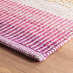 a pink and white rug sitting on top of a wooden floor