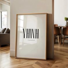 a white framed poster with the word yhw on it in front of a living room