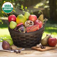 a basket filled with assorted fruit and nuts on top of a wooden table next to a cutting board