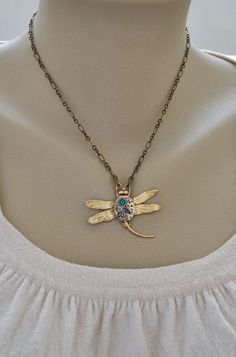 Vintage 17 jeweled watch movement mounted on top of brass Victorian style dragonfly and accented with blue zircon rhinestone on top. Pendant hangs on 16 antiqued brass chain with lobster clasp. All metal parts torch soldered together. Please allow minor differences for each watch movement than sample pictures shown. Measurement, Pendant is about 1.9 inch (48mm) wide on 16 inch chain. If you have a preferred length for the chain, please let me know in message to seller box and I will adjust it be Nickel-free Gold Dragonfly Jewelry, Steampunk Bronze Pendant Jewelry, Bronze Steampunk Pendant Jewelry, Steampunk Gold Necklace With Vintage Charm, Steampunk Gold Jewelry With Adjustable Chain, Gold Steampunk Jewelry With Adjustable Chain, Steampunk Gold Jewelry With Antique Finish, Steampunk Gold Brass Necklace, Gold Steampunk Nickel-free Jewelry