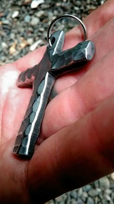 a hand holding a small piece of metal in it's palm, which is shaped like a cross