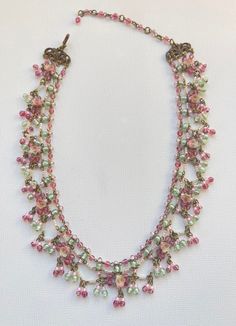 a necklace with pink, green and white beads