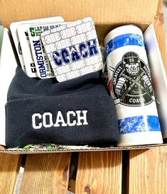 an open box containing coffee and other items on a wooden table with the word coach printed on it