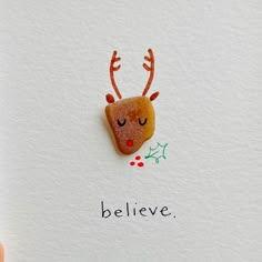 a hand holding up a christmas card with a reindeer face