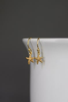 "Dainty and petite 24k gold vermeil starfish charms dangle from 18k gold vermeil balled earwires. Perfect small earrings for anyone of any age. Gold star charms: 8x9mm Total length of earrings: almost 1\" All gold is gold vermeil. As the owner, maker, designer, and curator of this shop, I take great pride in providing you with jewelry that you will love to wear everyday, for special occasions, and for many years to come. Please read my Shop Policies which contains important information regarding 14k Gold Filled Earrings With Star Charm As Gift, Yellow Gold Star Earrings For Everyday, Everyday Star-shaped Yellow Gold Earrings, Everyday Yellow Gold Star Earrings, Yellow Gold Star-shaped Pierced Earrings, Everyday Yellow Gold Earrings With Star Charm, Starfish-shaped Earrings With Star Charm For Gift, Starfish Earrings With Star Charm As Gift, Starfish Ear Wire Jewelry As Gift