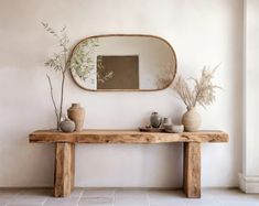 a wooden table with vases on it and a large mirror above the table in front of it