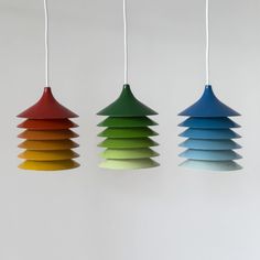 three multicolored lamps hanging from strings in the shape of christmas trees on a white wall