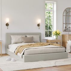 a bedroom with white walls and wood flooring has a large bed in the middle