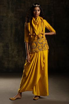 Yellow chanderi silk kurta with zardozi and beads embroidery . Paired with a draped skirt and scarf.
Component: 3
Pattern: Embroidery
Type Of Work: Zardozi, Beads
Neckline: V-Neck
Sleeve Type: Elbow length
Fabric: Kurta and Scarf: Chanderi Silk, Draped Skirt : Satin Linen
Color: Yellow
Other Details: 
Zardozi and beads embroidery
Draped skirt
Attached lining
Approx weight (in kg) : 1
Note: The blue outfit worn by the model on the right is not for sale
Note: The head accessory worn by the model i Embroidery Zardozi, Bridal Mehndi Dresses, Yellow Kurta, Mehndi Dresses, Skirt Satin, Lehenga Designs Simple, Beads Embroidery, Silk Kurta, Draped Skirt