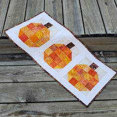 a quilted table runner with two pumpkins on it