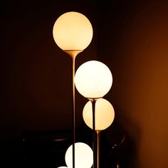 three white lamps sitting on top of a table next to each other in a dark room