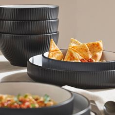 three bowls filled with food sitting on top of a table next to plates and utensils