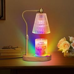 a colorful lamp sitting on top of a table next to a vase filled with flowers