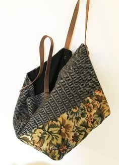 a handbag hanging on a wall with a brown leather strap and floral print fabric