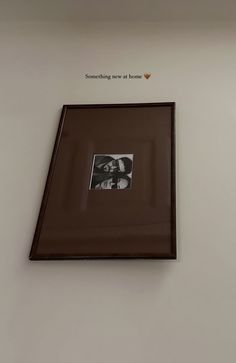 an old photo hanging on the wall in a room with white walls and brown trim