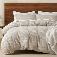 a bed with white linens and wooden headboard