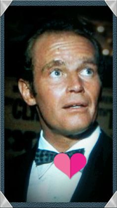 a man in a tuxedo with a pink heart on his lapel collar