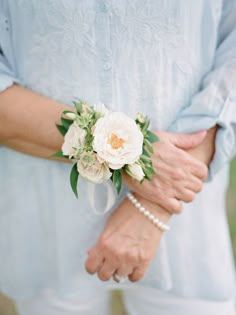 a close up of a person wearing a flower on their wrist and holding the other hand