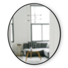 a round mirror reflecting a living room with a couch and coffee table in the background