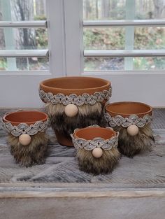 three planters with balls and fur on them sitting in front of a windowsill