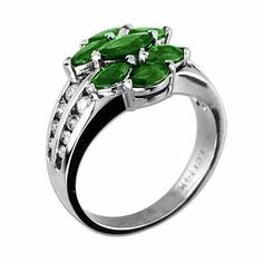 a ring with three green stones on top and white diamonds around the band, set in 18k white gold