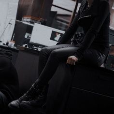 a woman sitting on top of a desk next to a man in a black suit