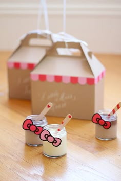 two little hello kitty dolls sitting on the floor next to a cardboard box with candy in it