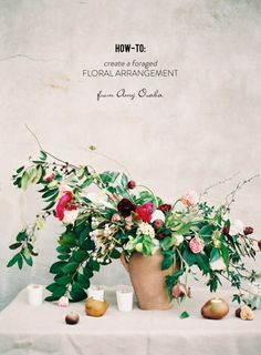 an arrangement of flowers and fruit on a table