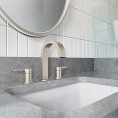 a bathroom sink sitting under a round mirror