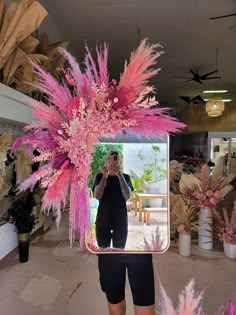 a woman taking a selfie in front of a mirror with pink feathers on it