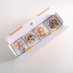 an open box with four different types of donuts in it on a white surface