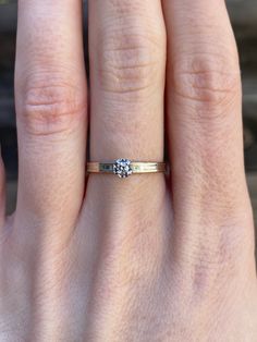 a woman's hand with a diamond ring on top of her finger, showing the band