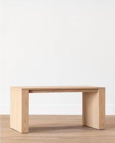 a wooden table sitting on top of a hard wood floor next to a white wall