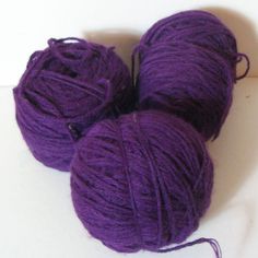 three balls of purple yarn on a white surface