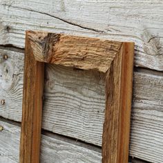 an old wooden frame hanging on the side of a wood planked wall with nails sticking out of it