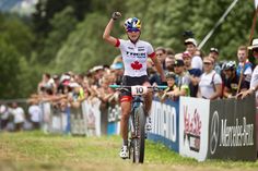 a man riding a bike on top of a lush green field next to a crowd