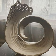 a white sculpture sitting on top of a table next to a window