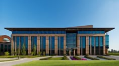 a large building with lots of windows on the side of it and green grass in front