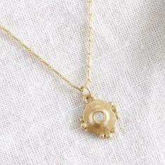 This small but mighty pendant is round with small granulation details on the top, bottom and sides, and bezel set with a white diamond. Product details: Pendant only, chain sold separately Materials: 18k gold pendant Measurements: .5 inch x .5 inch Gold Plated Birthstone Necklace With Round Pendant, Heirloom Diamond Medallion Necklace, Yellow Gold Pendant Charm Necklace With Satellite Chain, Heirloom Medallion Diamond Necklace, Yellow Gold Diamond Necklace With Satellite Chain, Tarnish-resistant Diamond Round Pendant Necklace, Round Brass Jewelry With Bezel Setting, Tarnish-resistant Diamond Necklace With Round Pendant, Tarnish Resistant Diamond Necklace With Round Pendant