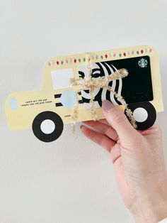 a person holding up a card with a zebra on the front and a bus on the back