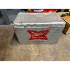 an old metal box sitting on the floor next to some boxes and other items in a garage