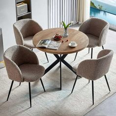 a round table with four chairs around it in a living room next to a window