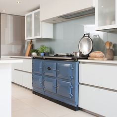 a blue stove top oven sitting inside of a kitchen next to white cabinets and counter tops