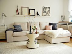 a living room with a white couch and some pictures on the wall above it's coffee table