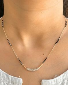 a woman wearing a necklace with black beads and a gold chain on her neck,