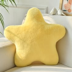 a yellow star pillow sitting on top of a white couch next to a potted plant