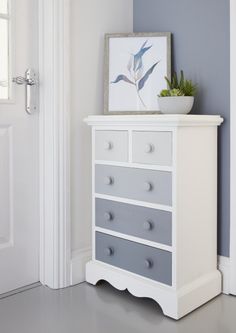 a white dresser with drawers and a potted plant on top