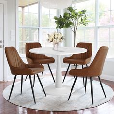 a white table with four brown chairs around it