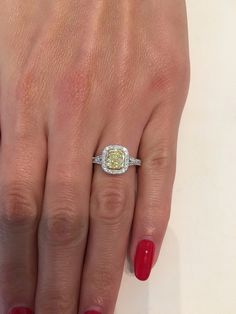 a woman's hand with red nail polish holding a yellow diamond ring on her finger