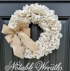 a white wreath with the words apple wreaths are hanging on a black front door